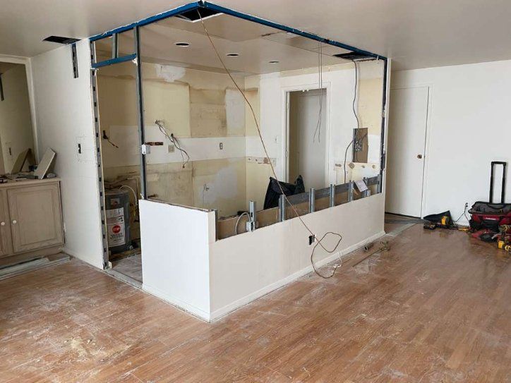 Interior undergoing renovation, with partial wall removal, exposed framing, and tools on floor.