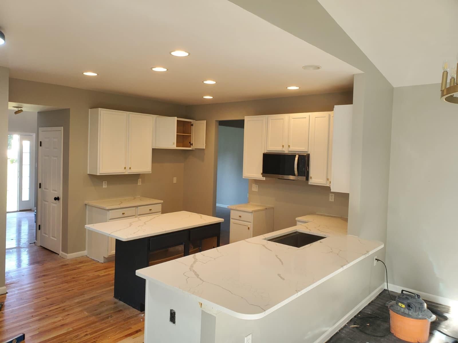 Newly renovated kitchen with white cabinets, dark island, and light countertops.