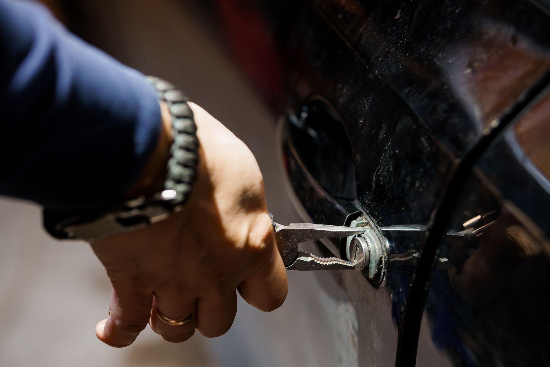 A Close-Up of a Hand Using Pliers to Manipulate a Car Door Lock A Close-Up of a Hand Using Pliers to Manipulate a Car Door Lock