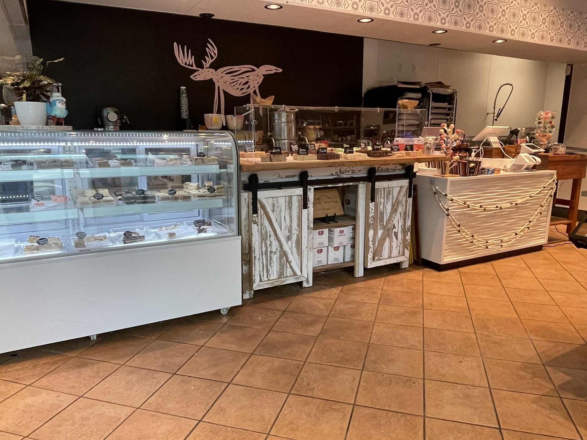 A chocolate shop interior with display cases, a counter, and a moose silhouette on a black wall.