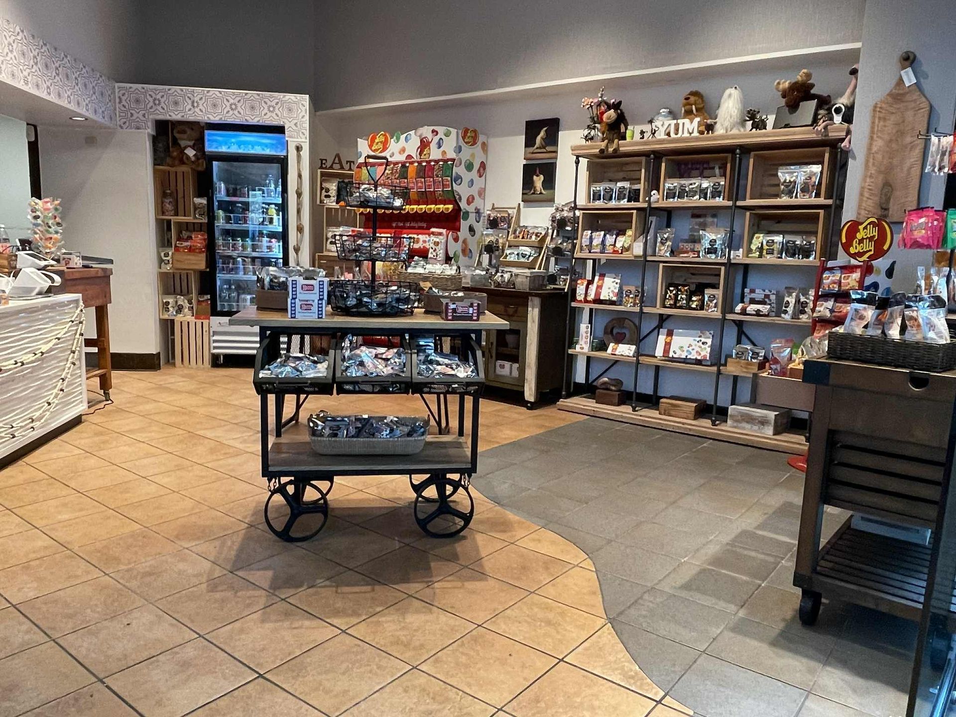 Interior of a shop with merchandise on shelves and a rolling cart. Flooring is tile.