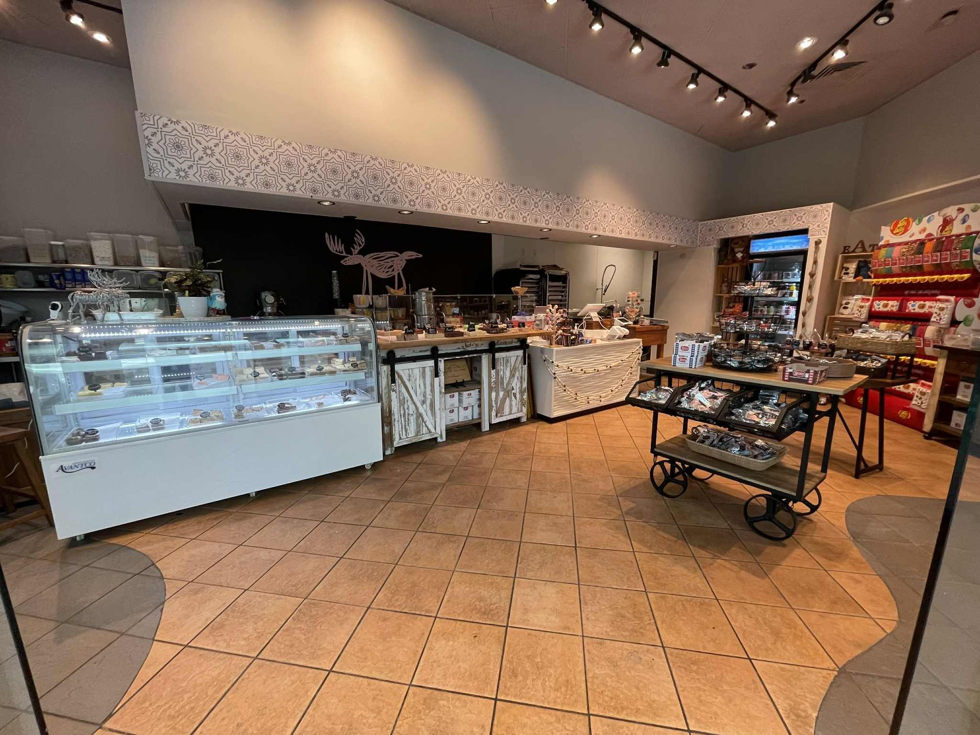 Interior of a gift shop with display cases, shelves, and a variety of items. Beige tile floor.
