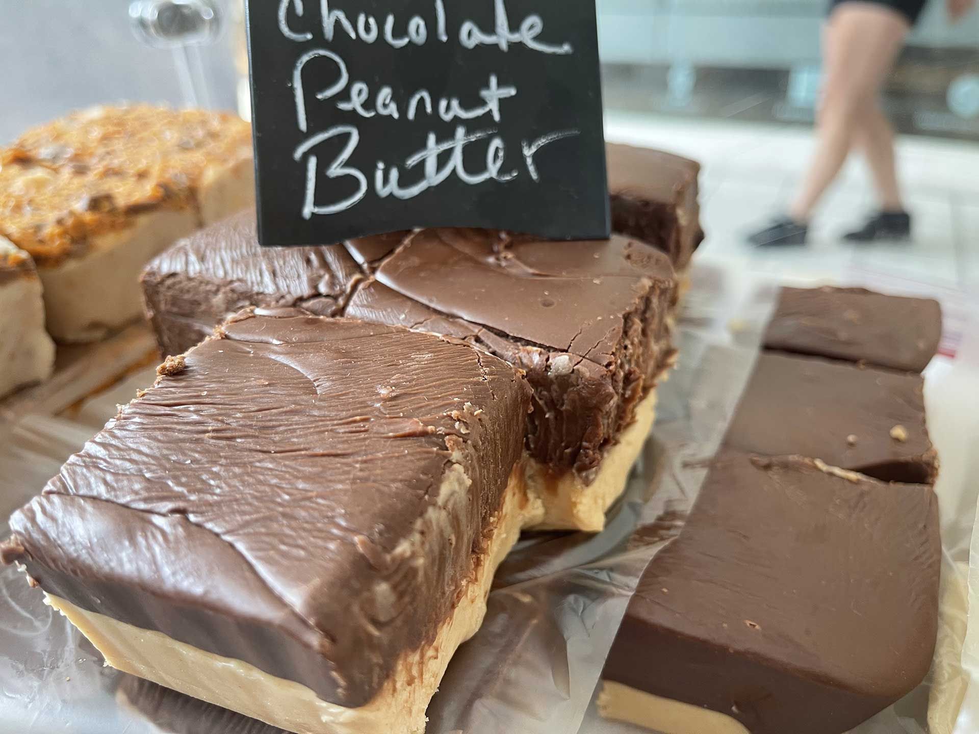 Chocolate peanut butter fudge on display with a black chalkboard sign.
