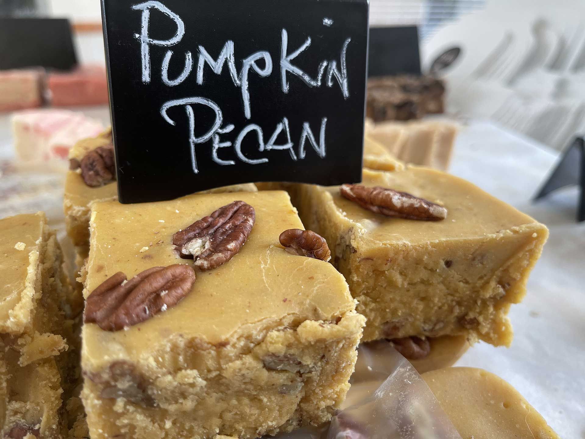 Pumpkin pecan fudge squares with pecan pieces, and a black sign that reads