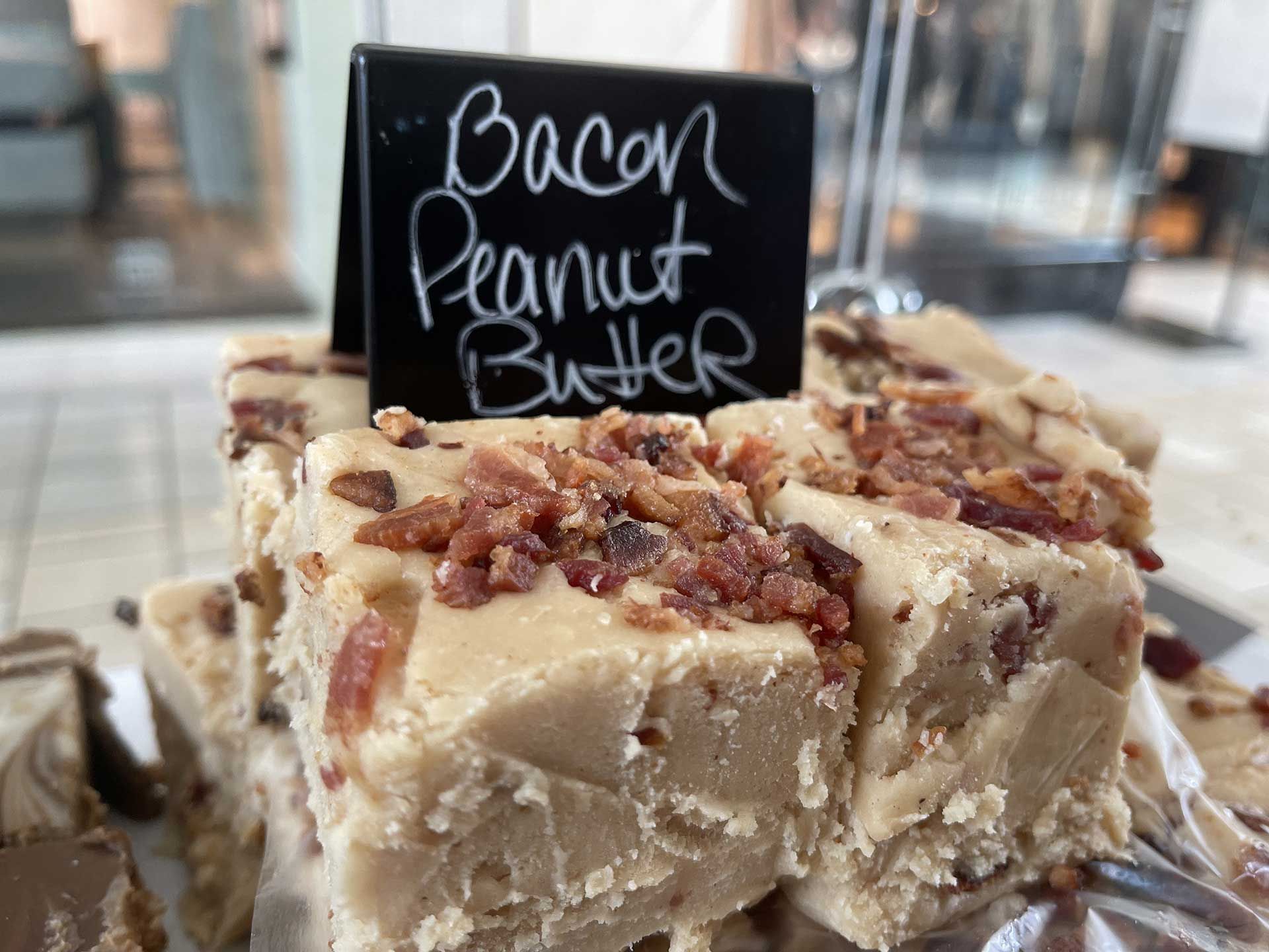 Bacon peanut butter fudge; beige with bacon bits on top; black sign.