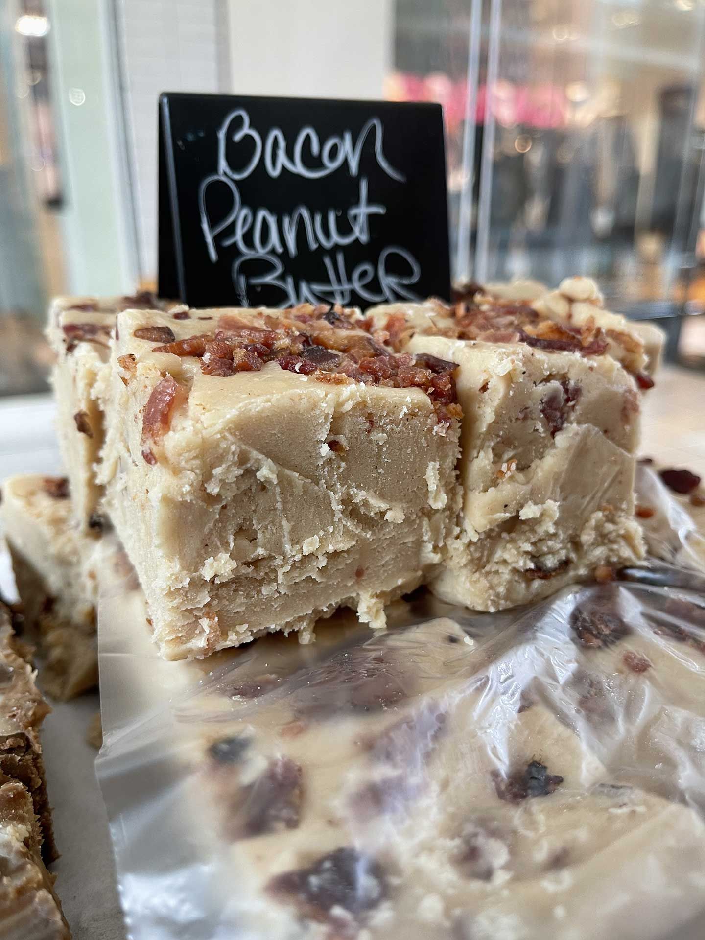 Bacon peanut butter fudge, cut into squares, with bacon crumbles on top. Sign reads