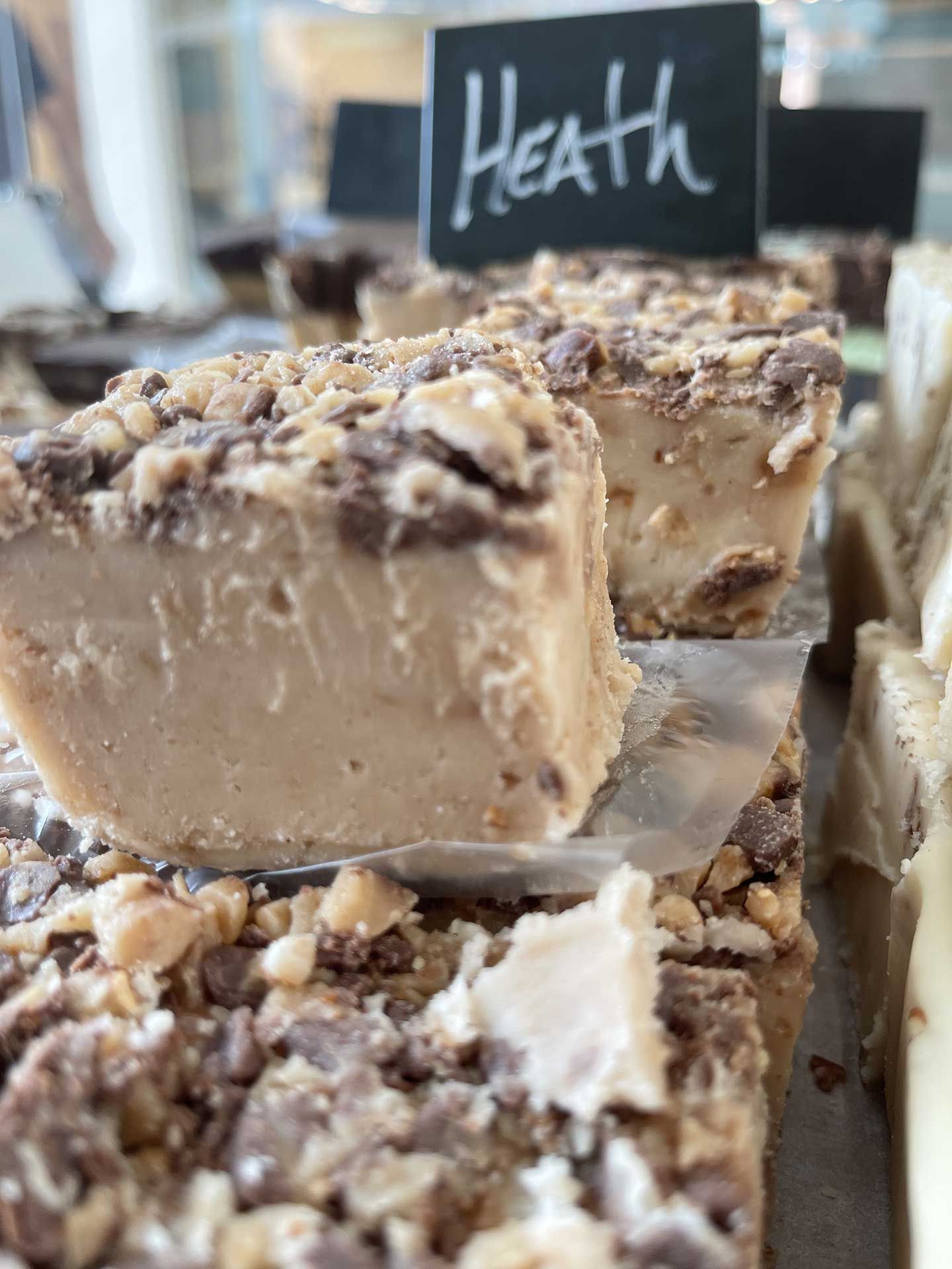 Close-up of Heath toffee fudge squares, topped with toffee bits. Sign reads