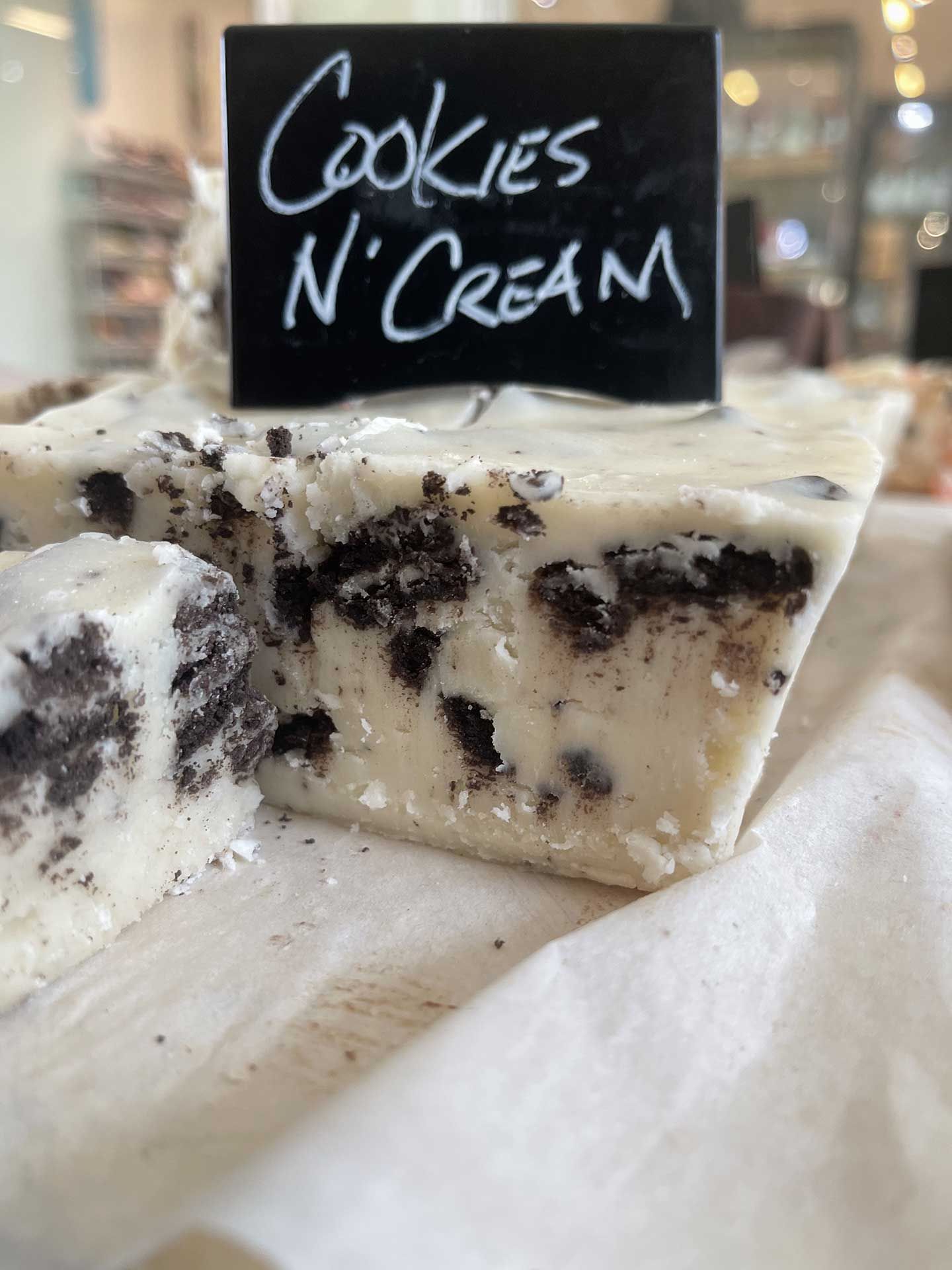 Cookies 'n Cream fudge with black cookie pieces, white background, and a handwritten sign.