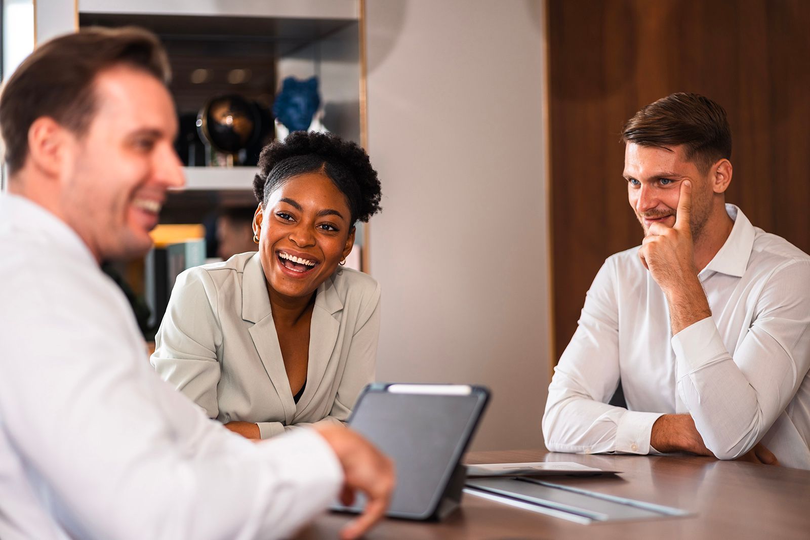 Three people smiling and laughing around a table in an office.