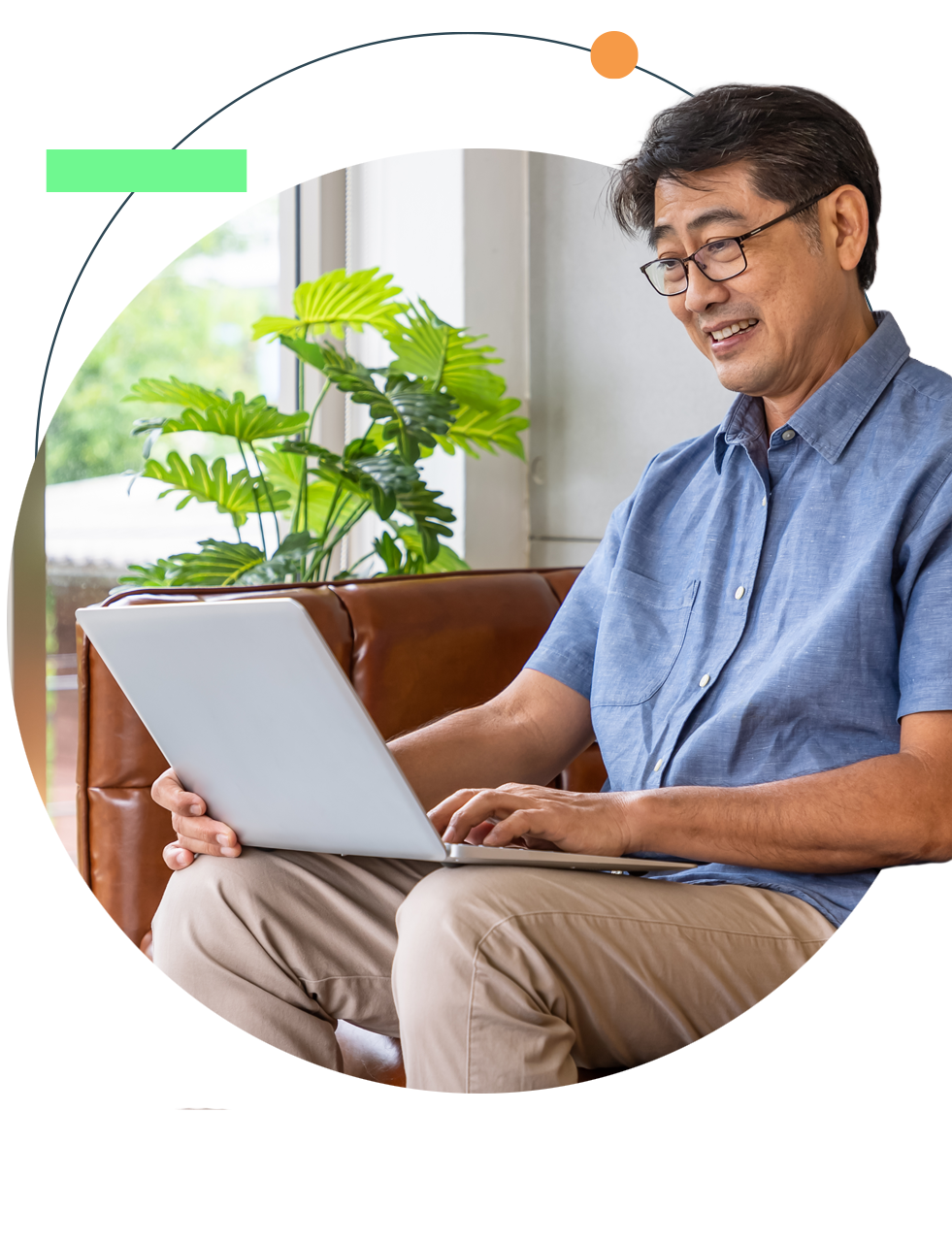 Man with glasses using a laptop, sitting on the floor next to a couch.