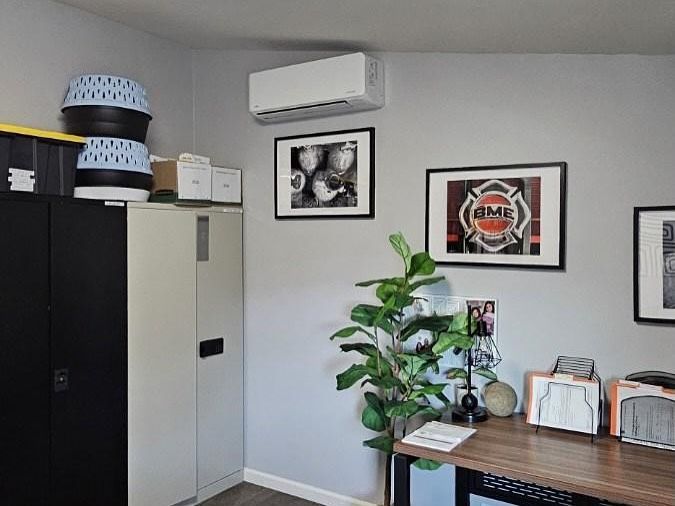 Office corner with filing cabinets, desk, potted plant, wall art, and an air conditioner