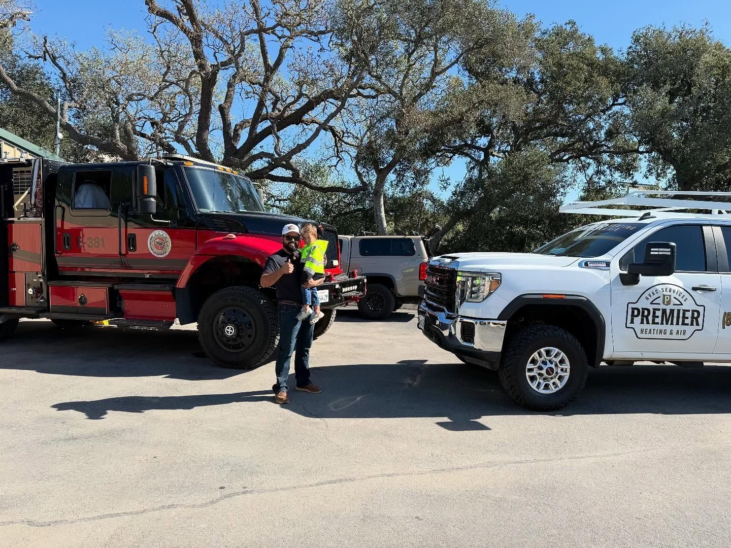Fire truck and Premier fire rescue truck parked roadside with a firefighter standing between them.