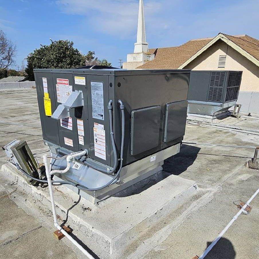 Roof-mounted HVAC unit on a concrete curb with ductwork and electrical connections