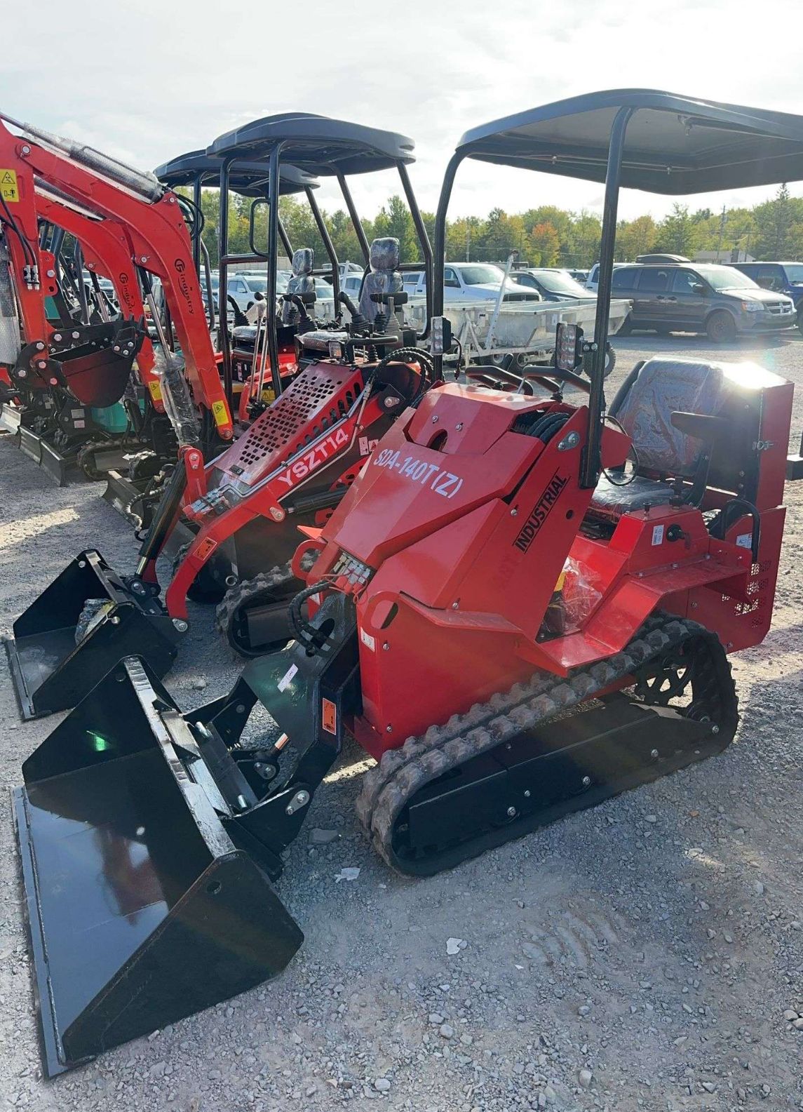 Several red compact construction vehicles with canopies, parked outdoors.