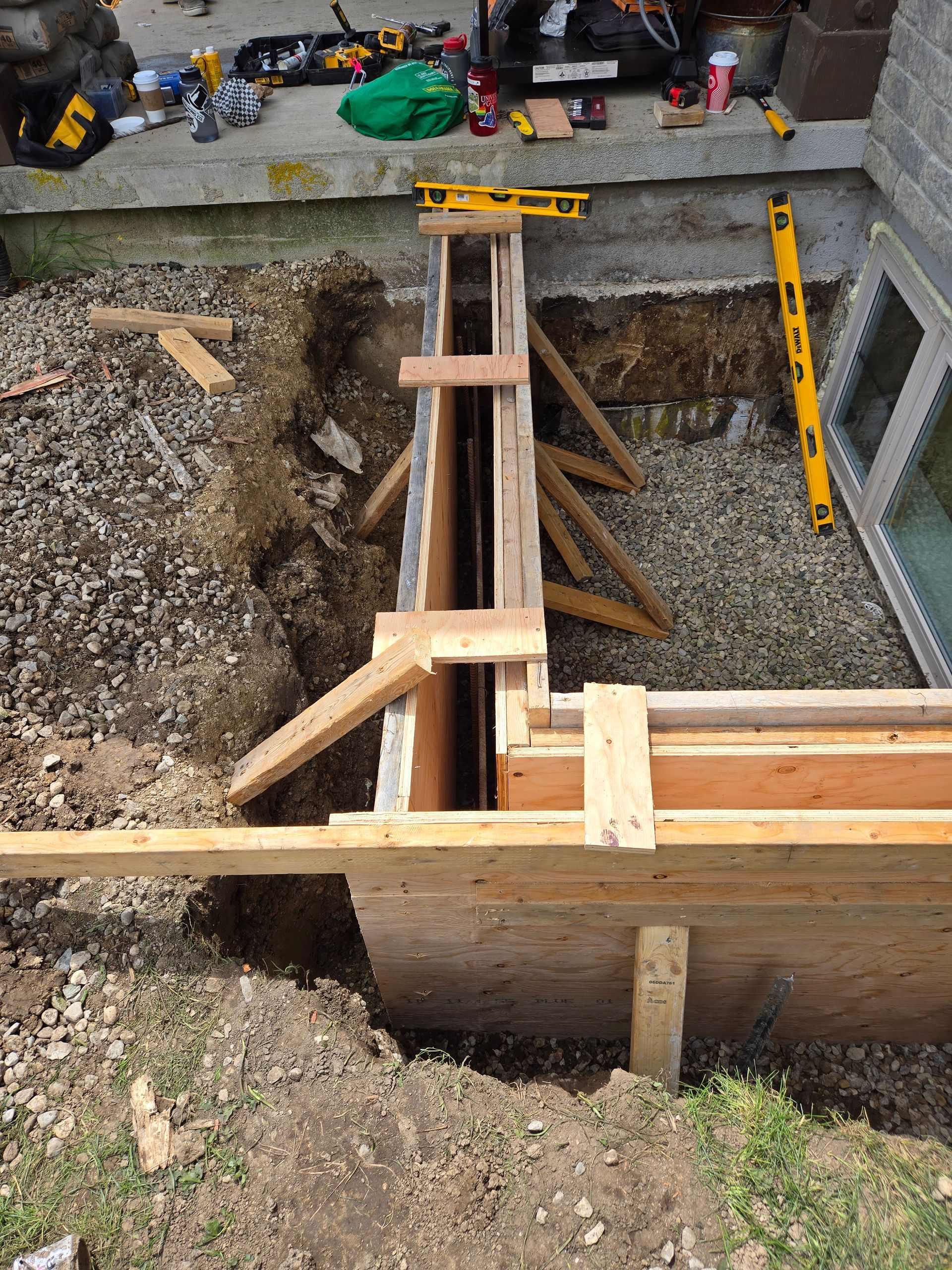 A wooden fence is being built in a hole in the ground.