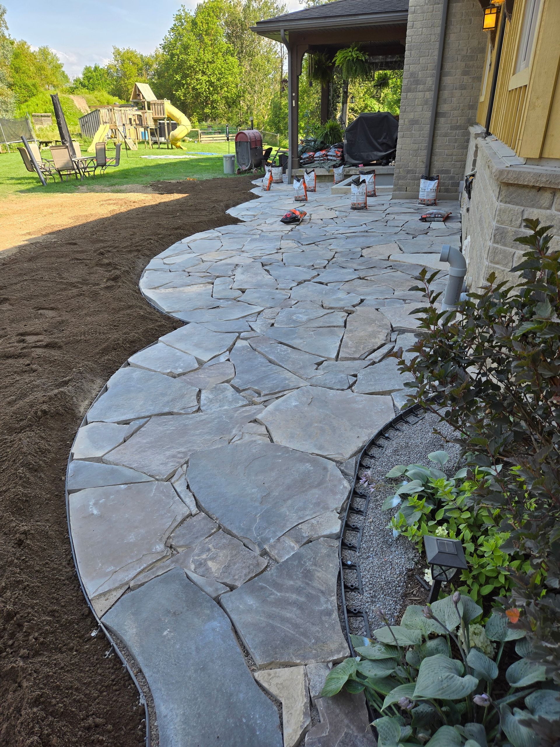 A stone walkway is being built in front of a house.