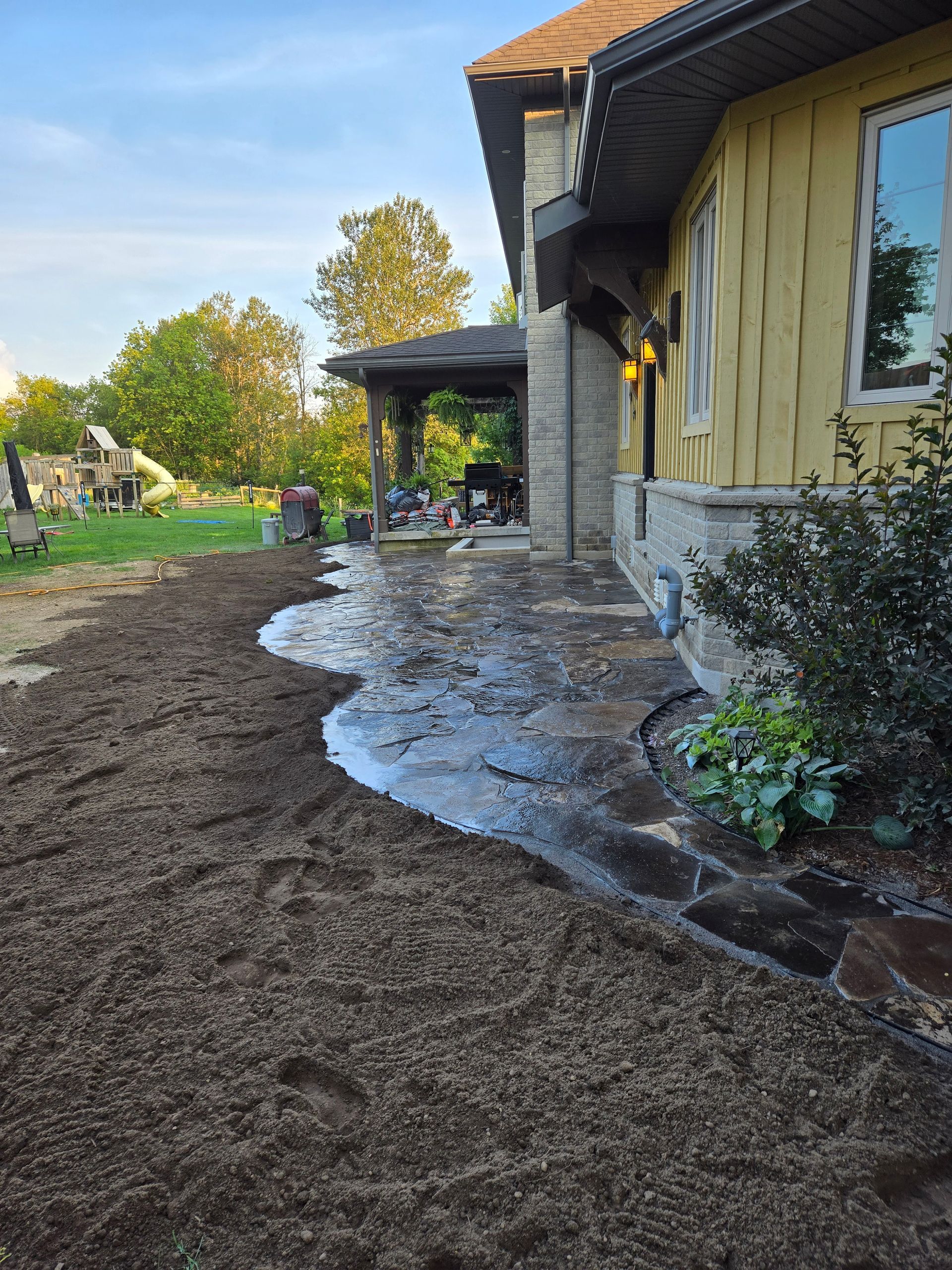 A house with a patio and a lot of dirt in front of it.