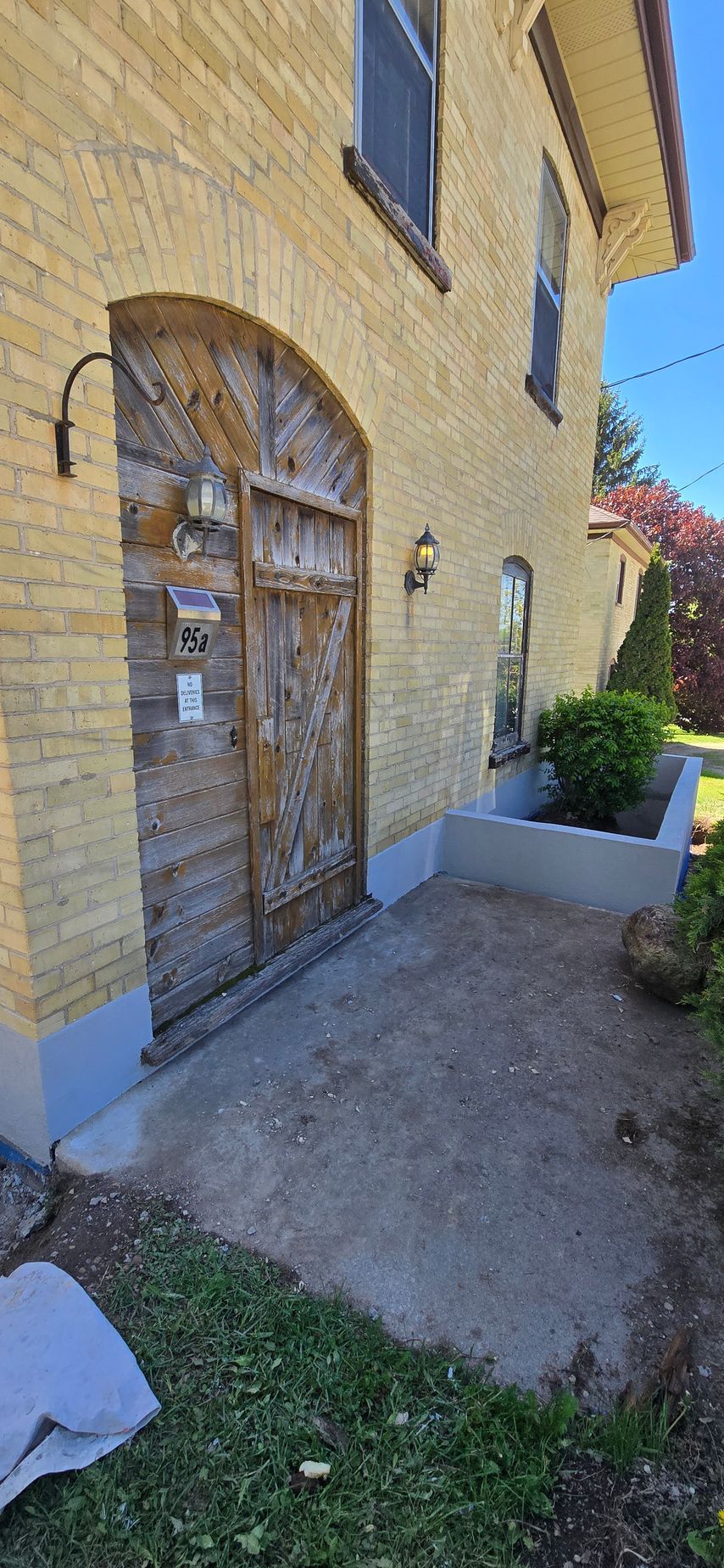 A brick building with a wooden door and a concrete walkway.