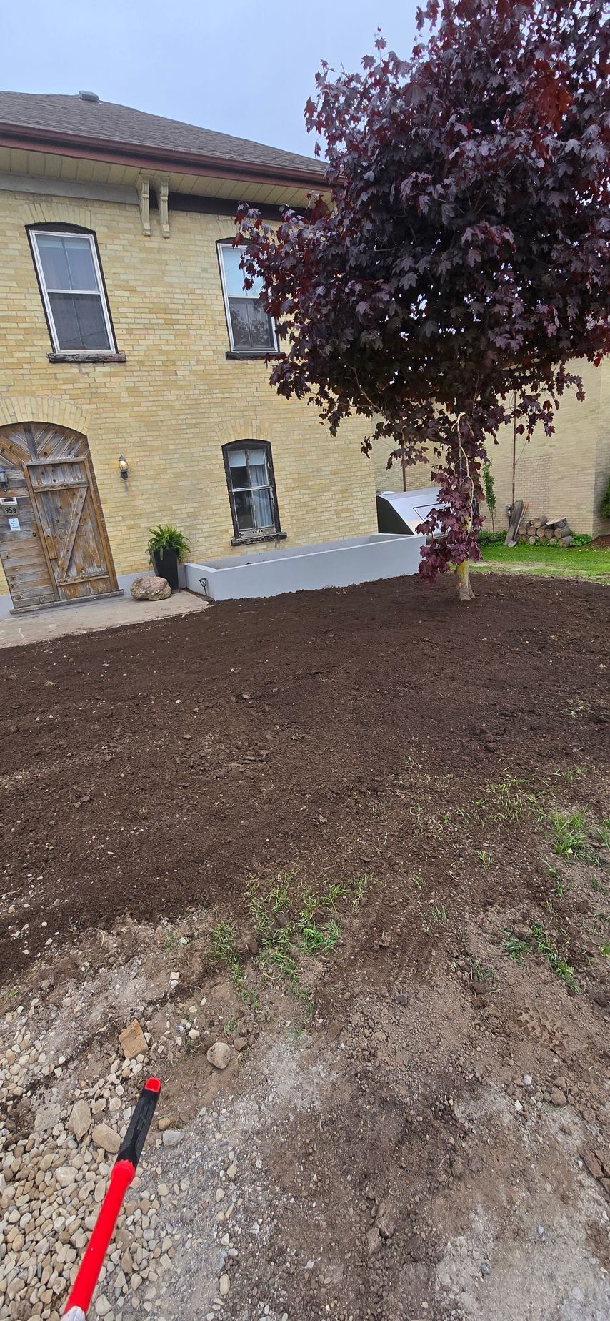 A shovel is sitting in the dirt in front of a house.