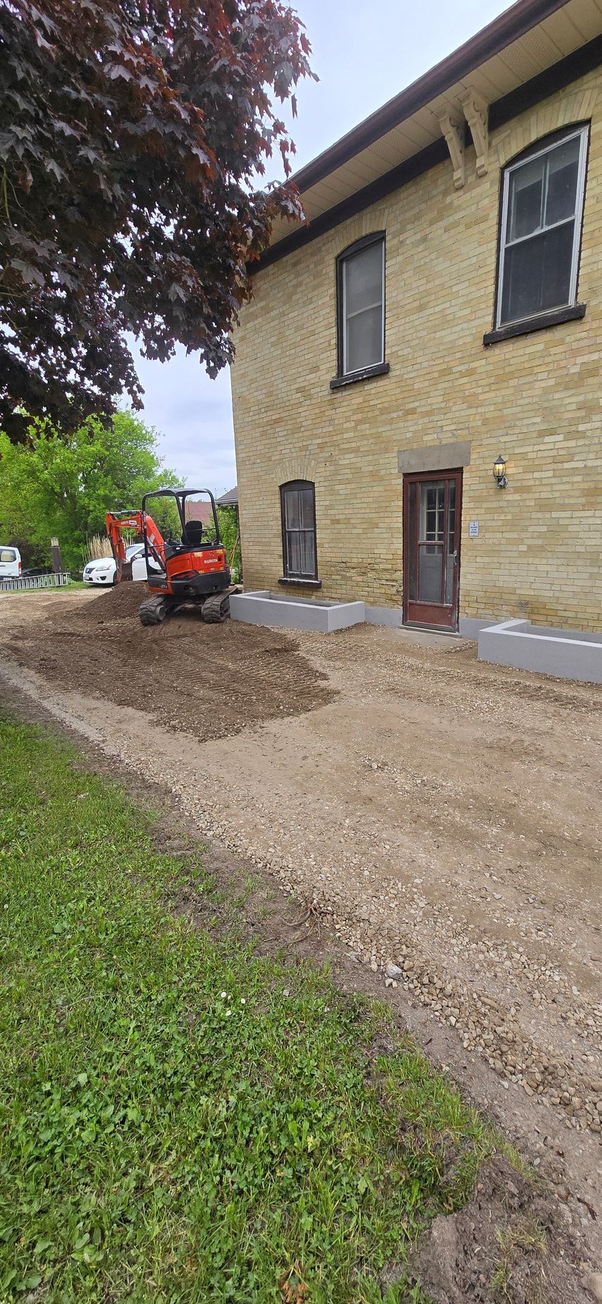A large brick building with a dirt driveway in front of it.
