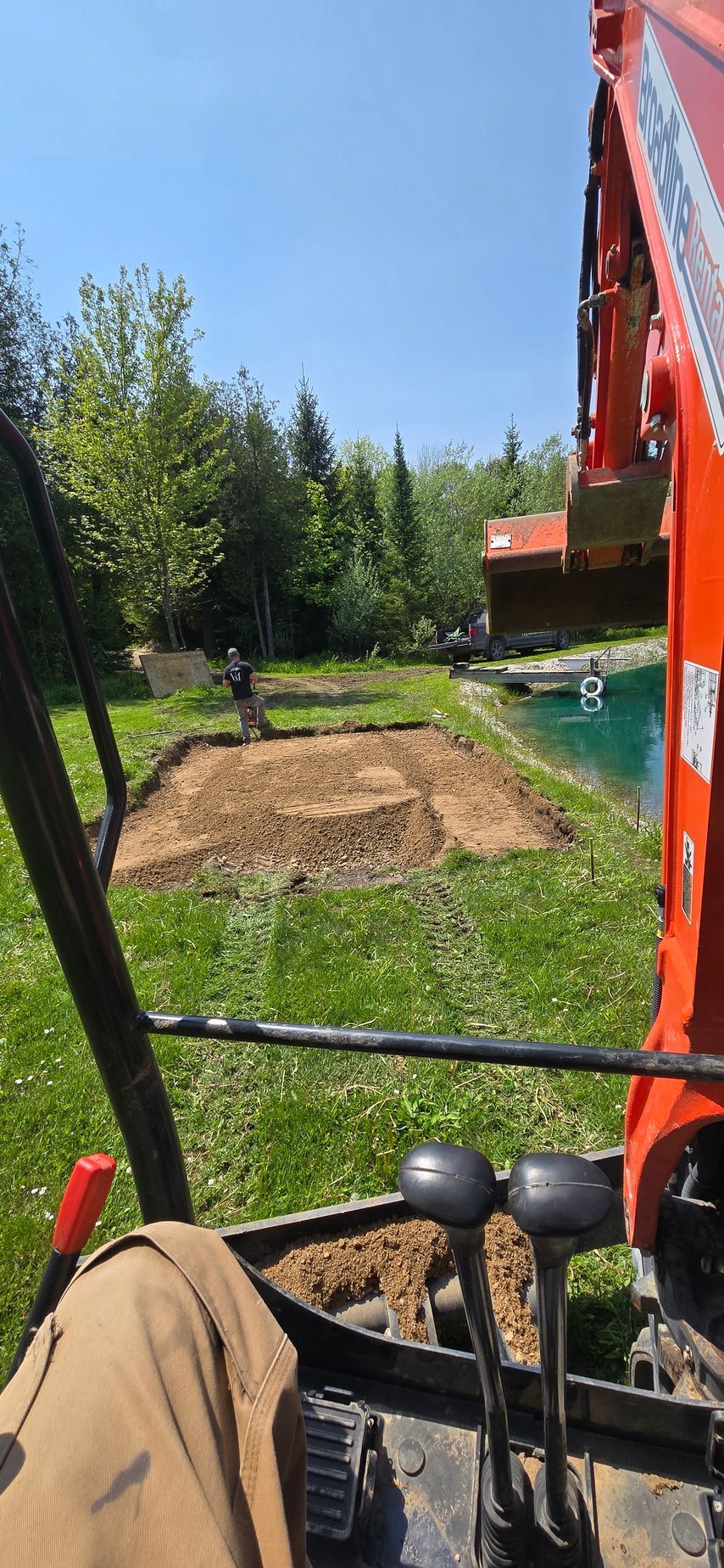 A person is driving an excavator in a backyard.