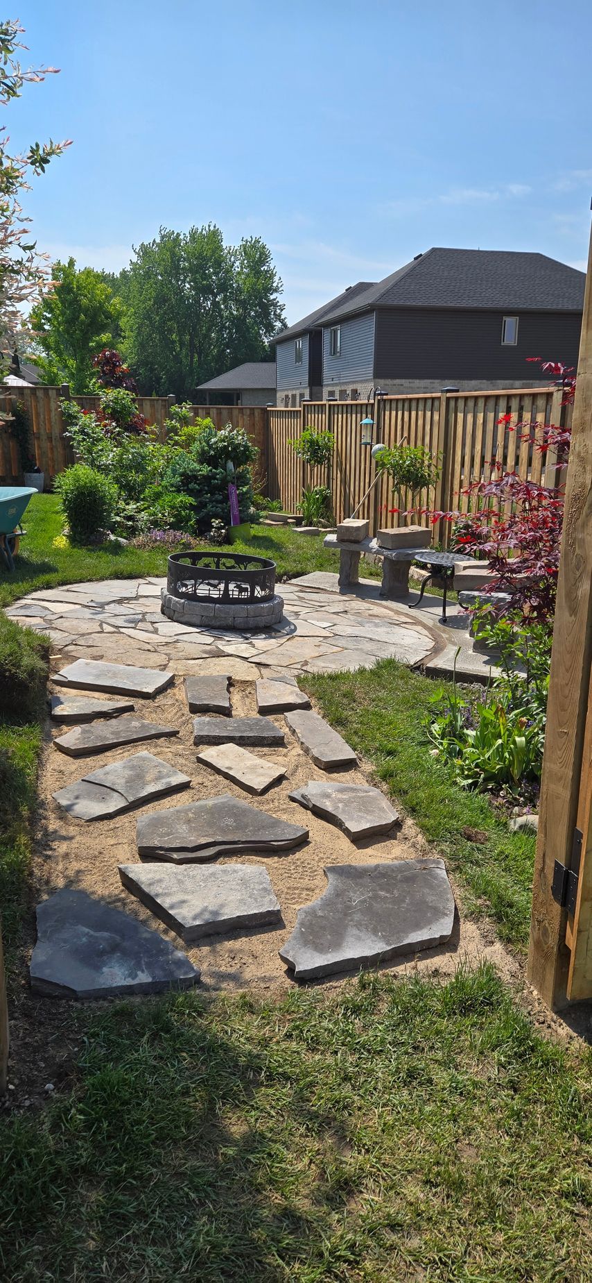 A stone walkway leading to a patio in a backyard.