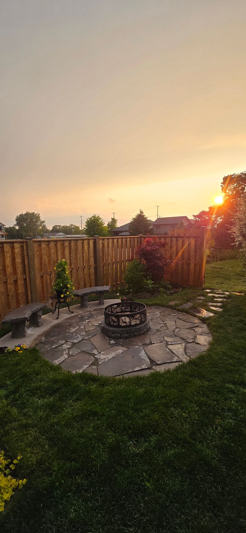 There is a fire pit in the middle of the backyard at sunset.