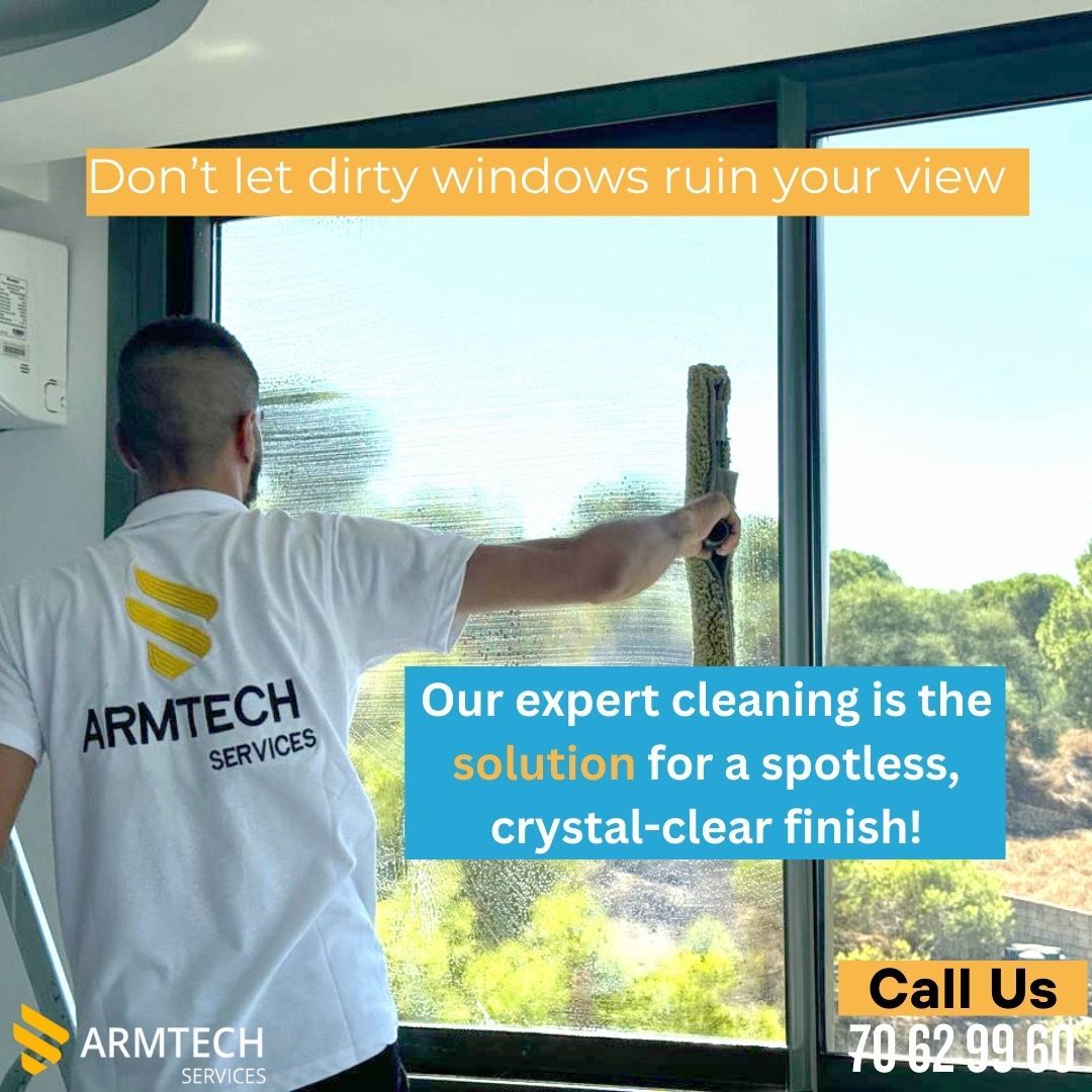 A man is cleaning a window with an armtech shirt on