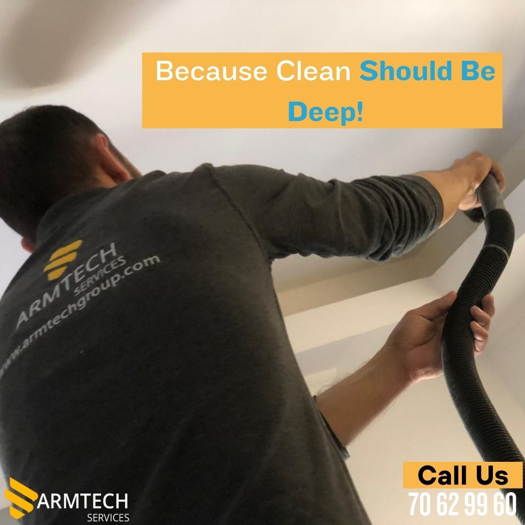 A man is using a vacuum cleaner to clean the ceiling