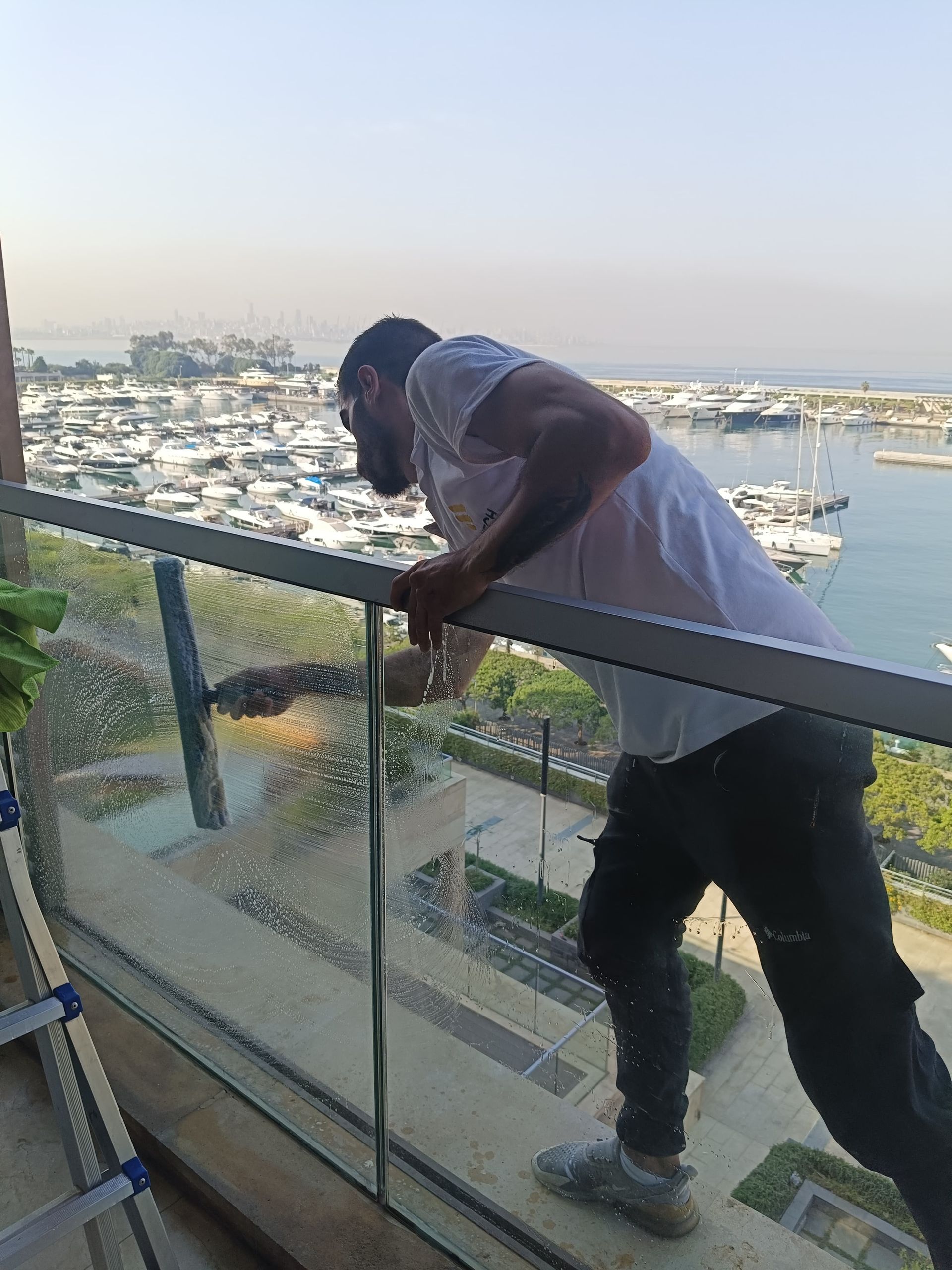 A man is cleaning a window on a balcony.