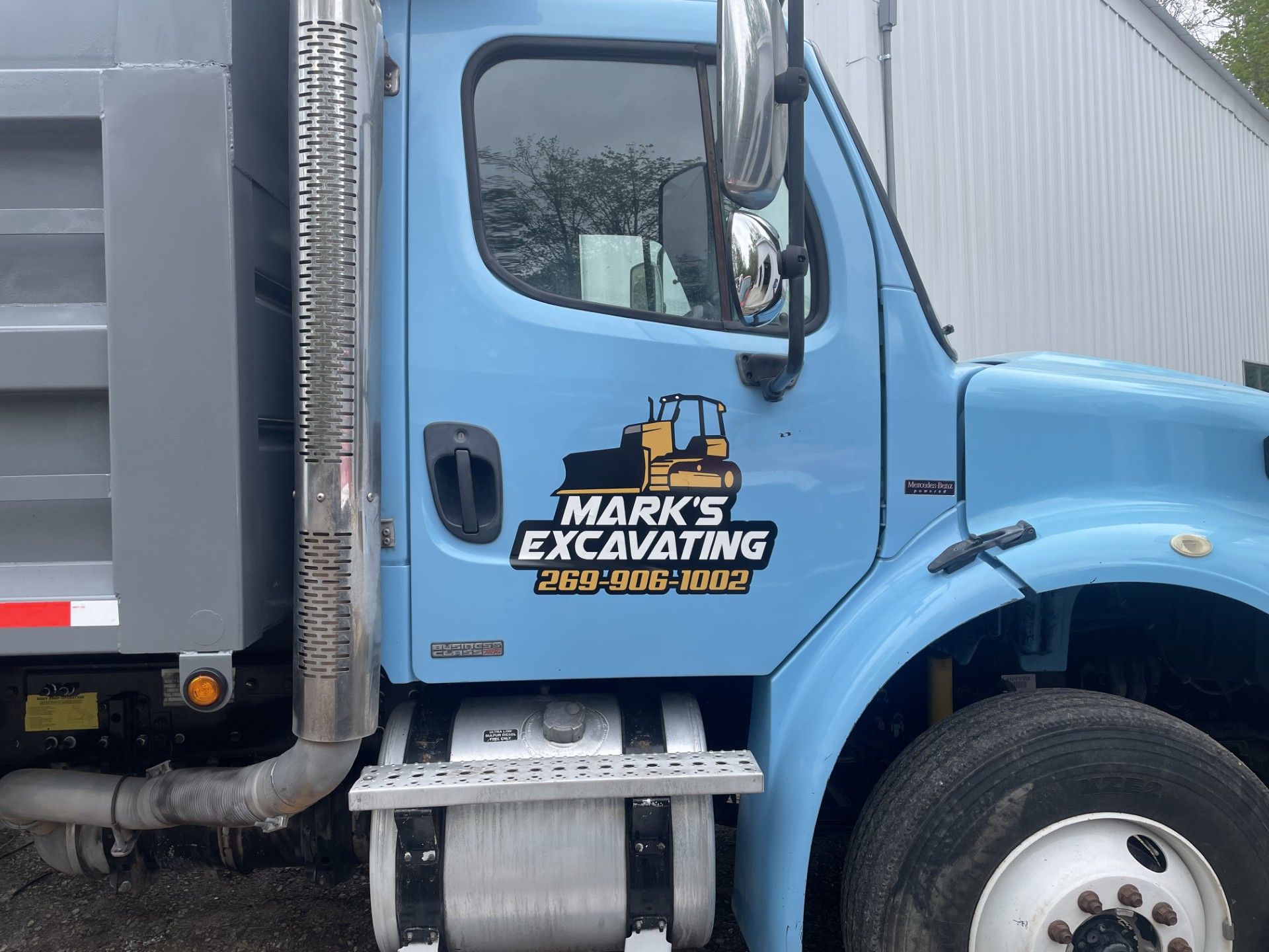 A blue dump truck with the words mark 's excavating on the side