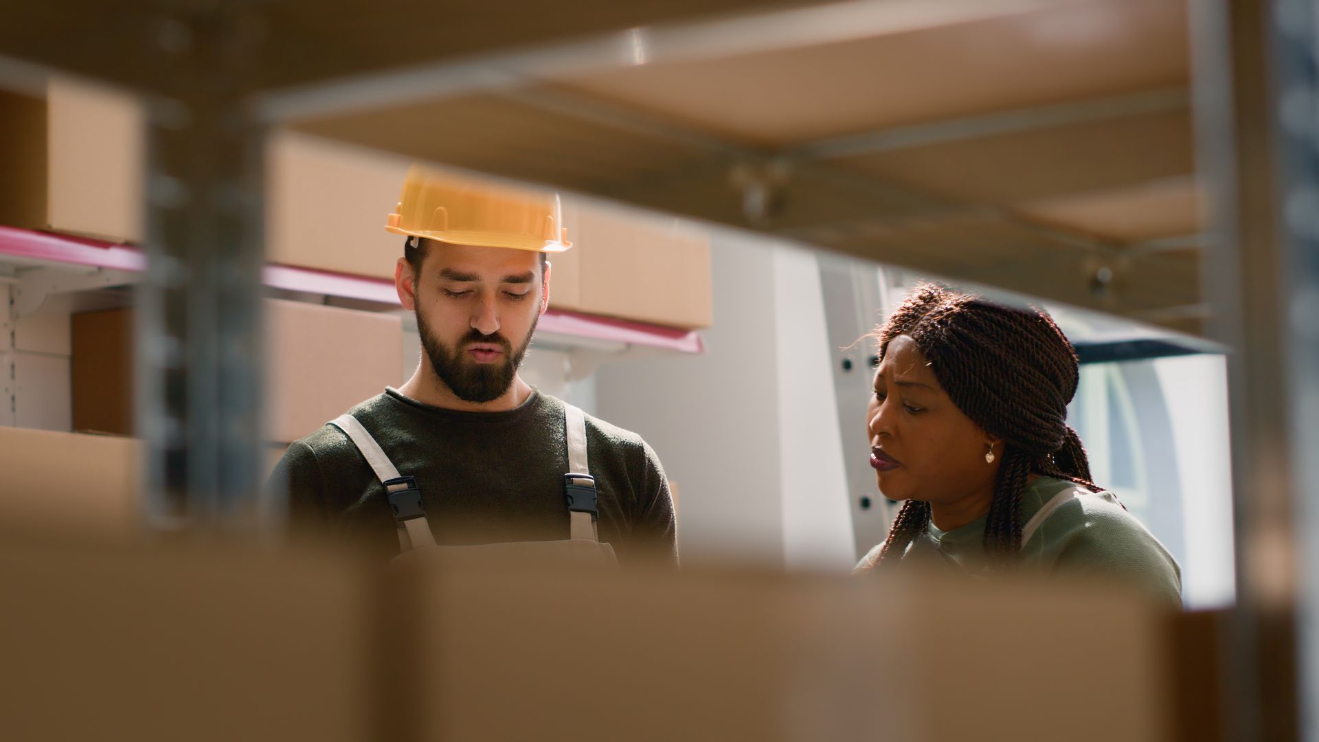 A man and a woman are standing next to each other in a warehouse looking at boxes.