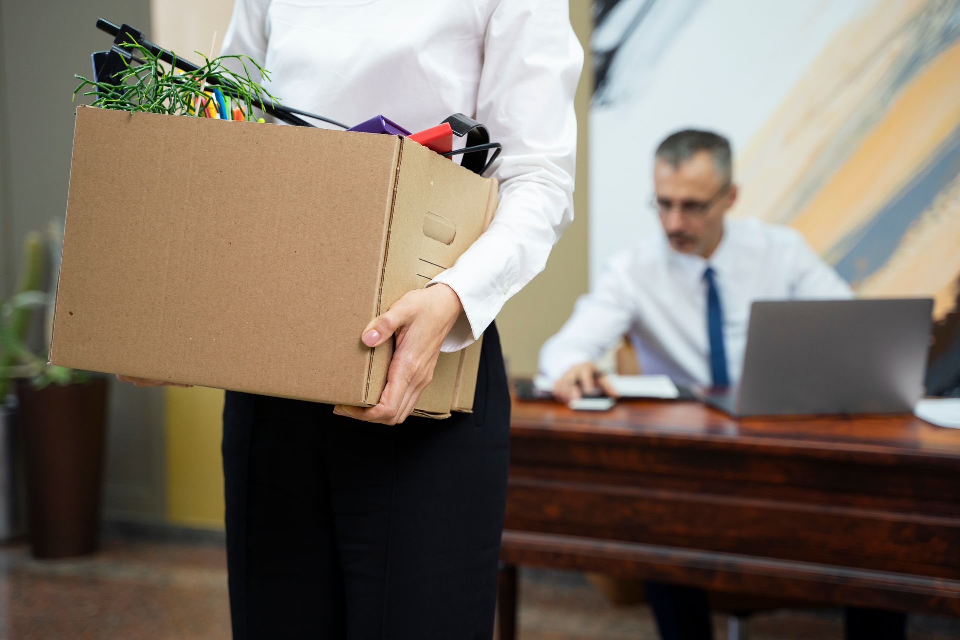 A woman is holding a cardboard box full of her belongings.