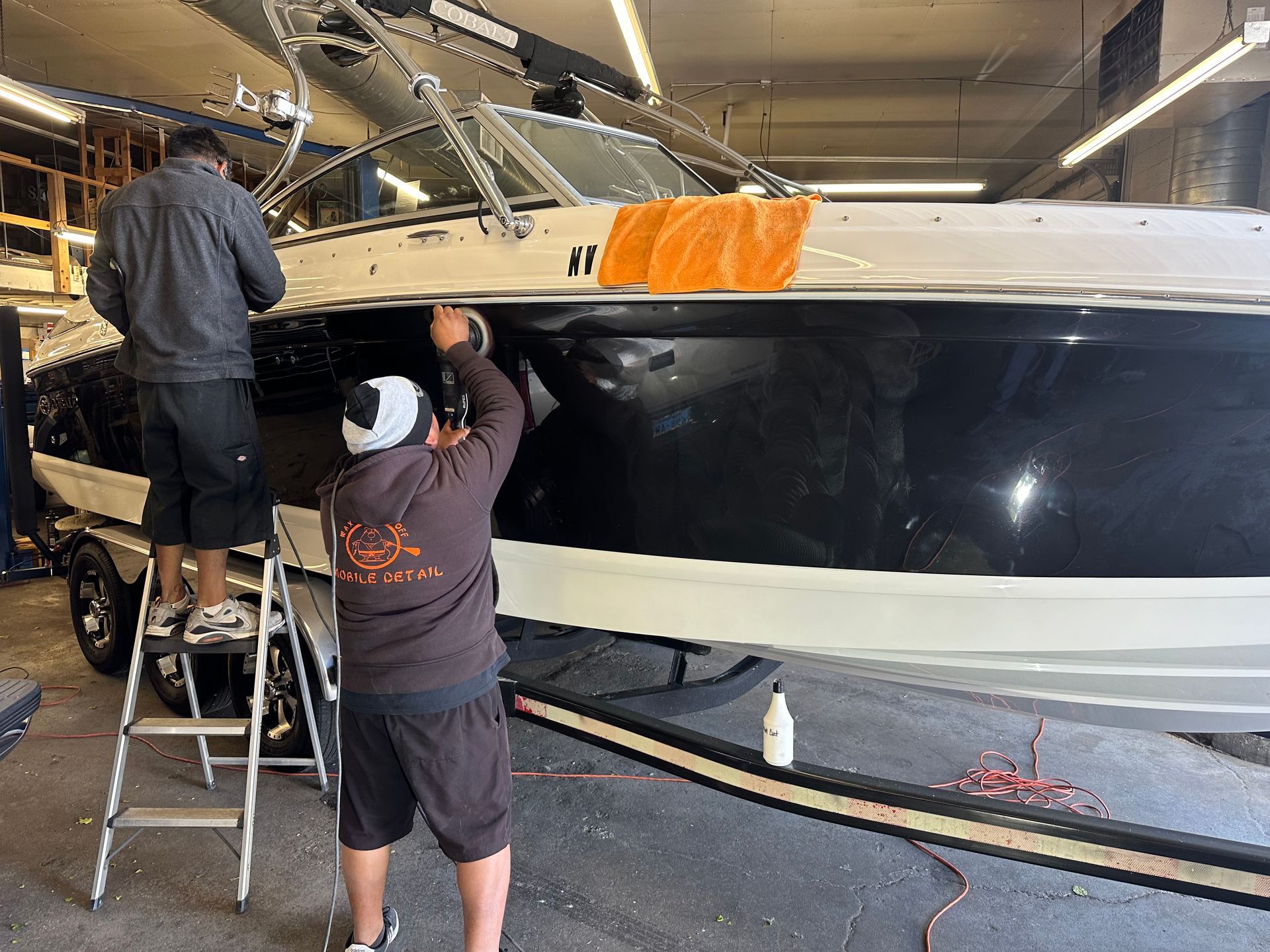 Two men are working on a boat in a garage.
