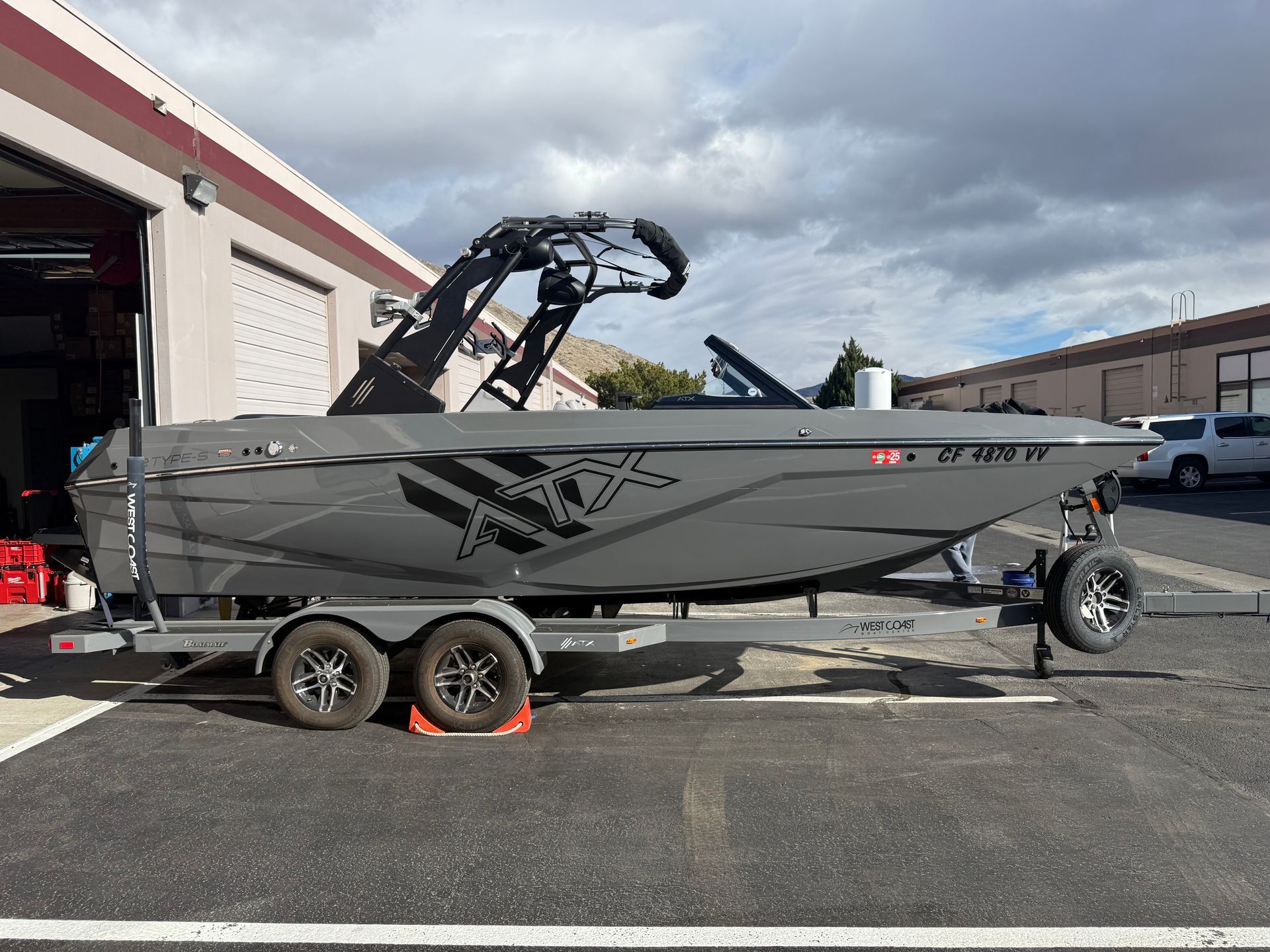 A boat is on a trailer parked in front of a garage.