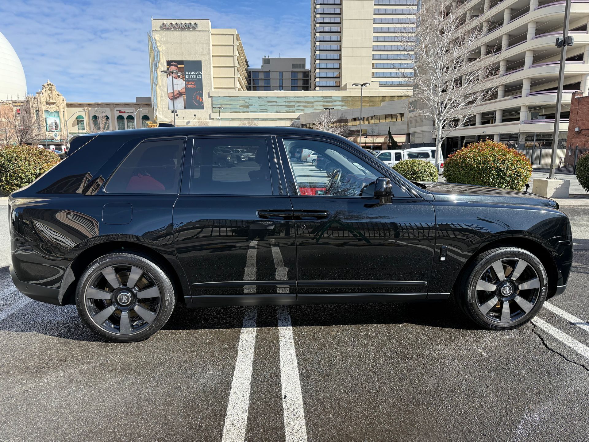 A black range rover is parked in a parking lot in front of a building.