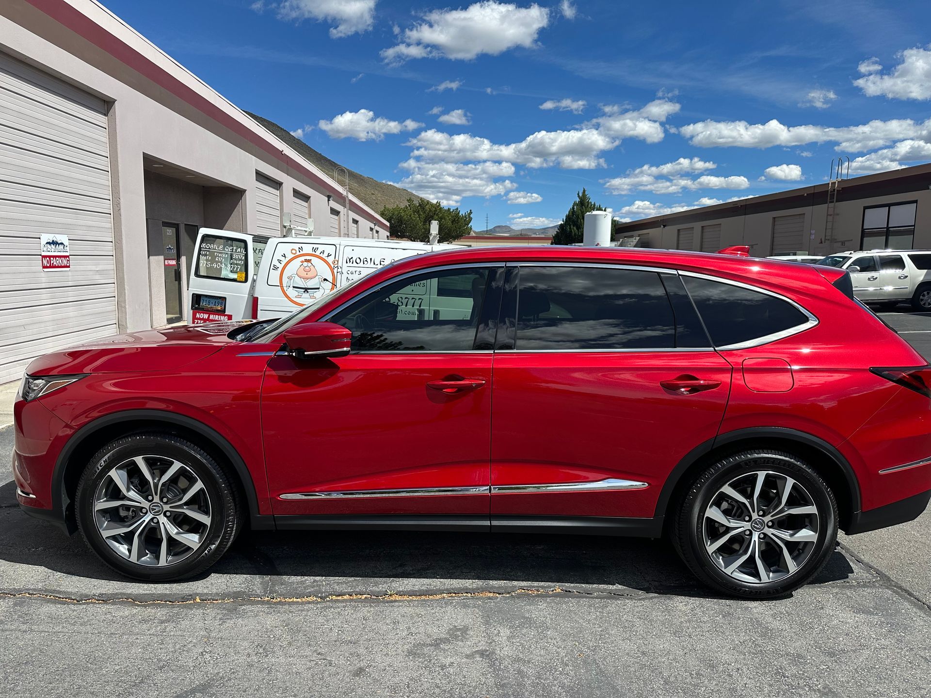 A red suv is parked in a parking lot in front of a building.