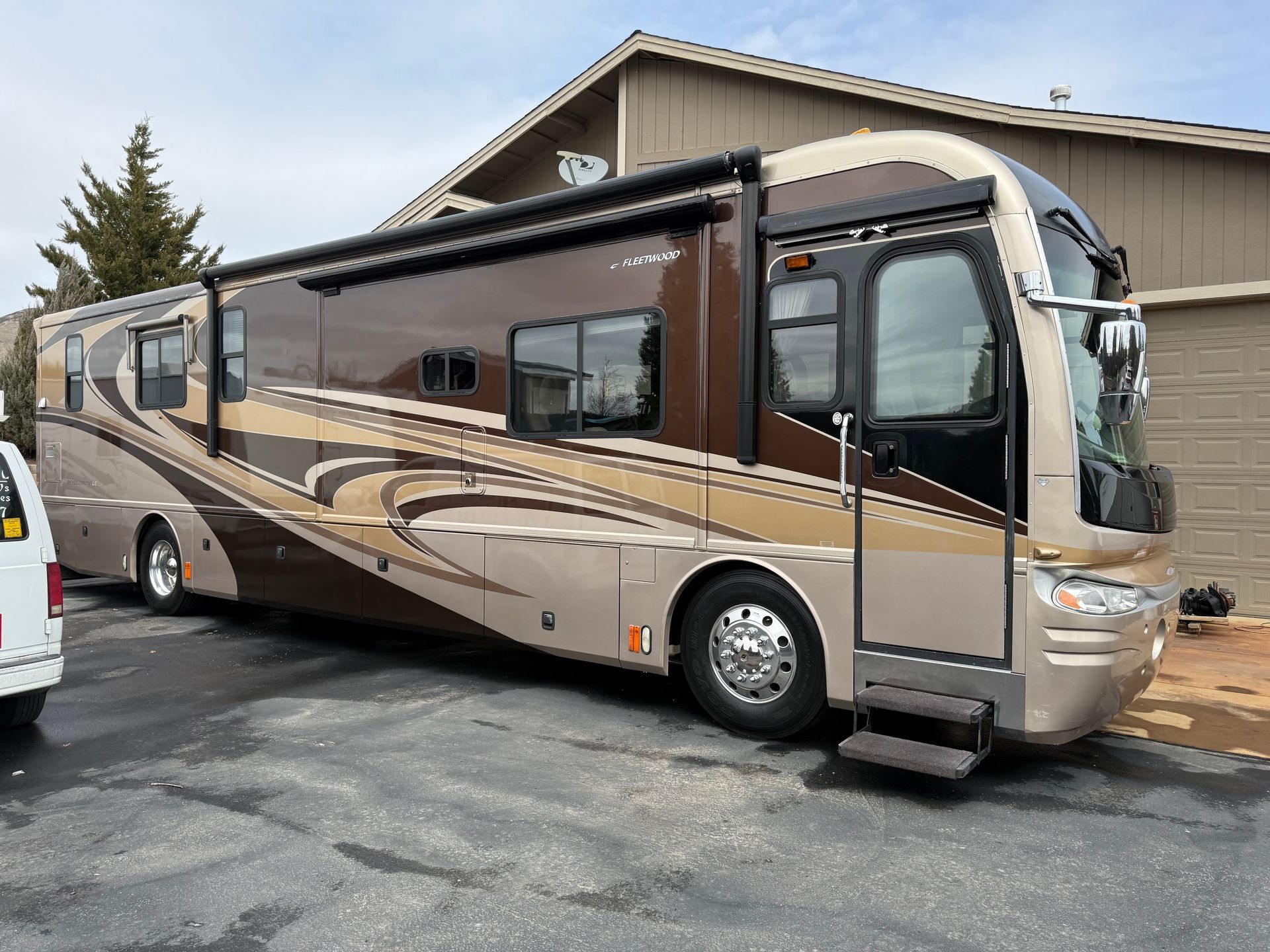 A large rv is parked in a parking lot in front of a house.