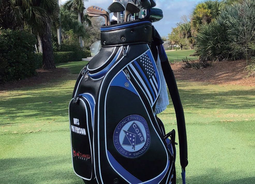 A black and blue golf bag is sitting on a golf course.