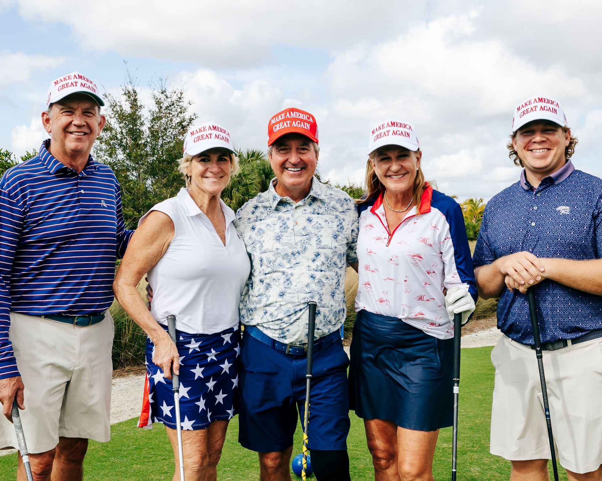 Five people pose on a golf course, wearing red 