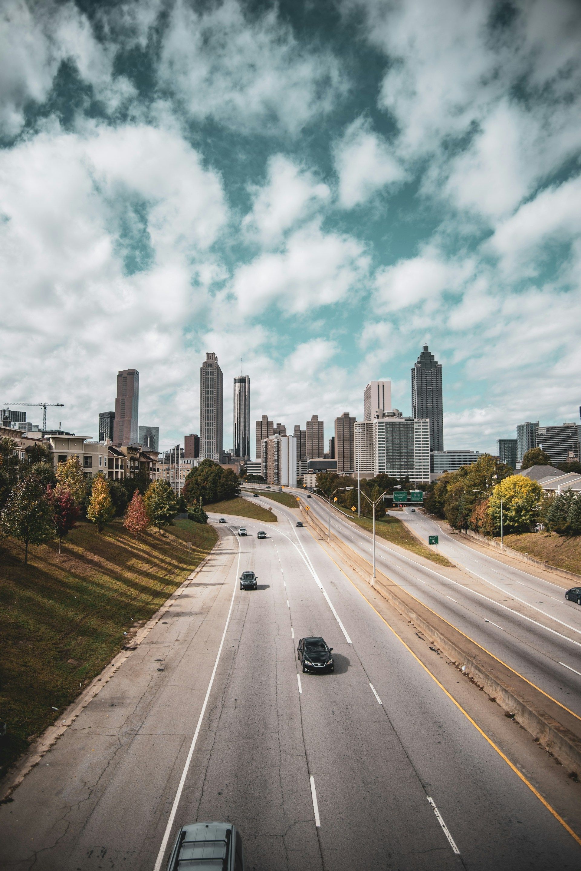 Atlanta skyline with highway in foreground and cloudy sky above.