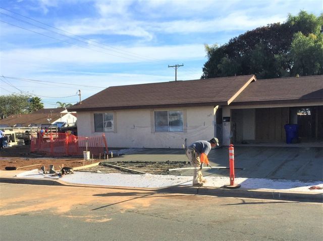 A man is working on a driveway in front of a house