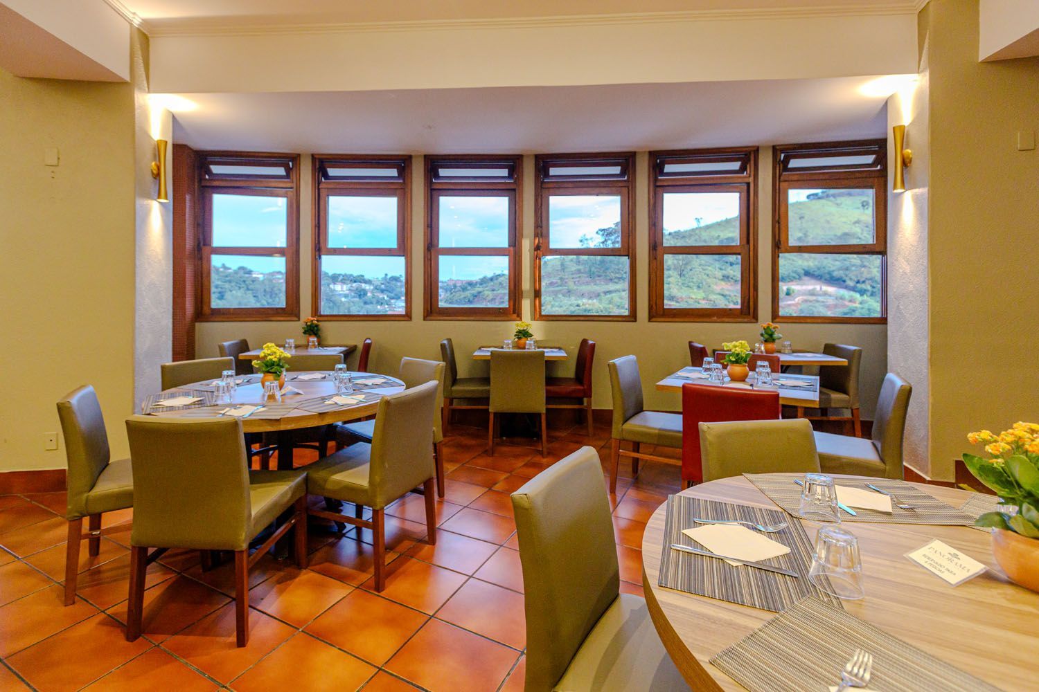 Um restaurante com mesas e cadeiras e muitas janelas