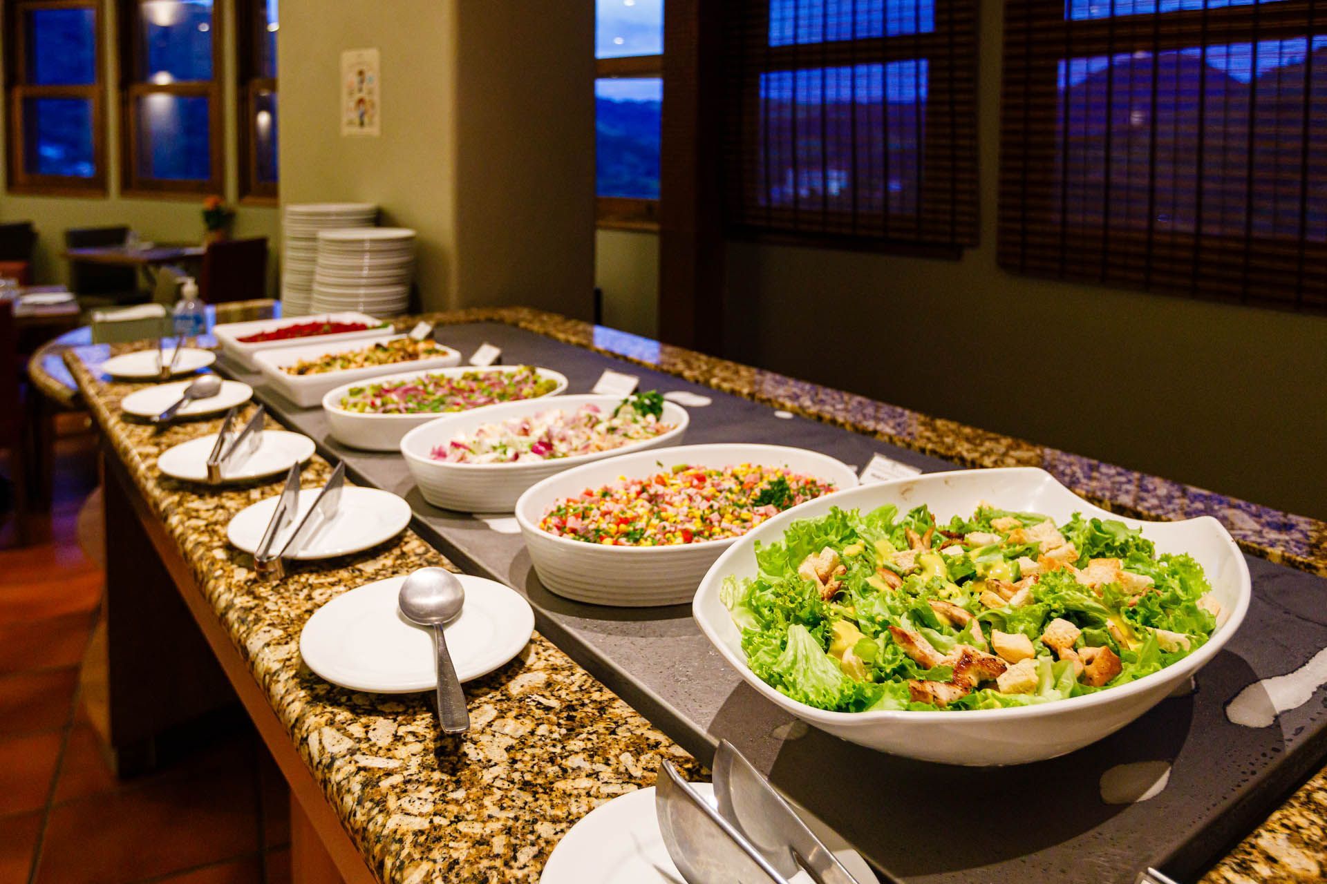 Uma mesa de bufê com pratos e tigelas de comida.
