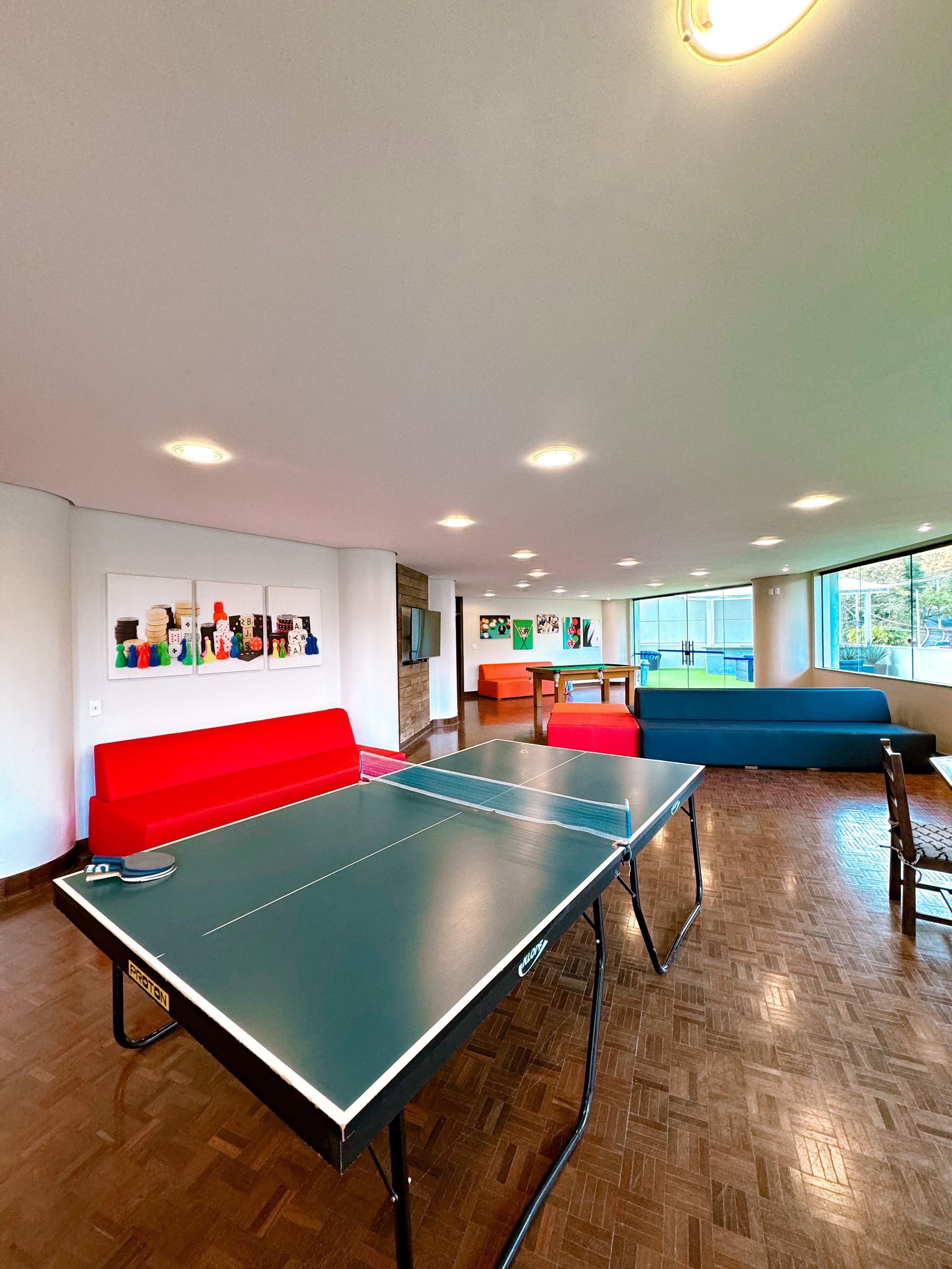Uma sala grande com uma mesa e cadeiras e uma mesa de pingue-pongue.