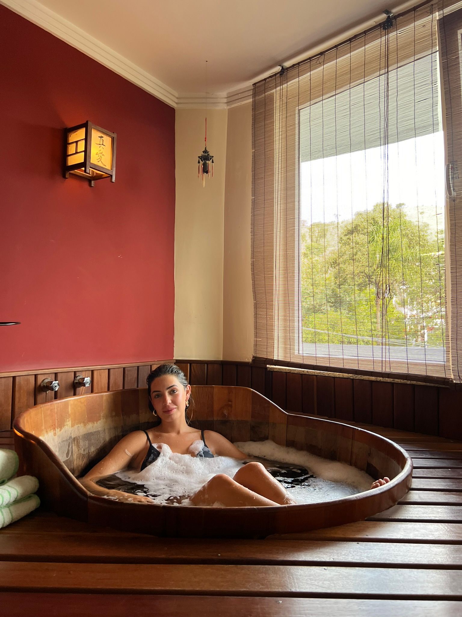 Uma banheira cheia de espuma rosa e velas em um banheiro.