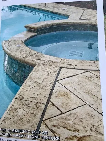 Stone hot tubs beside a blue swimming pool with beige tiled decking