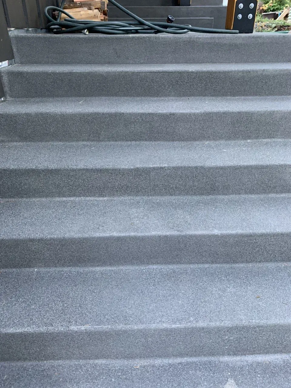 Gray carpeted stairs with a person lying at the top landing near equipment cables