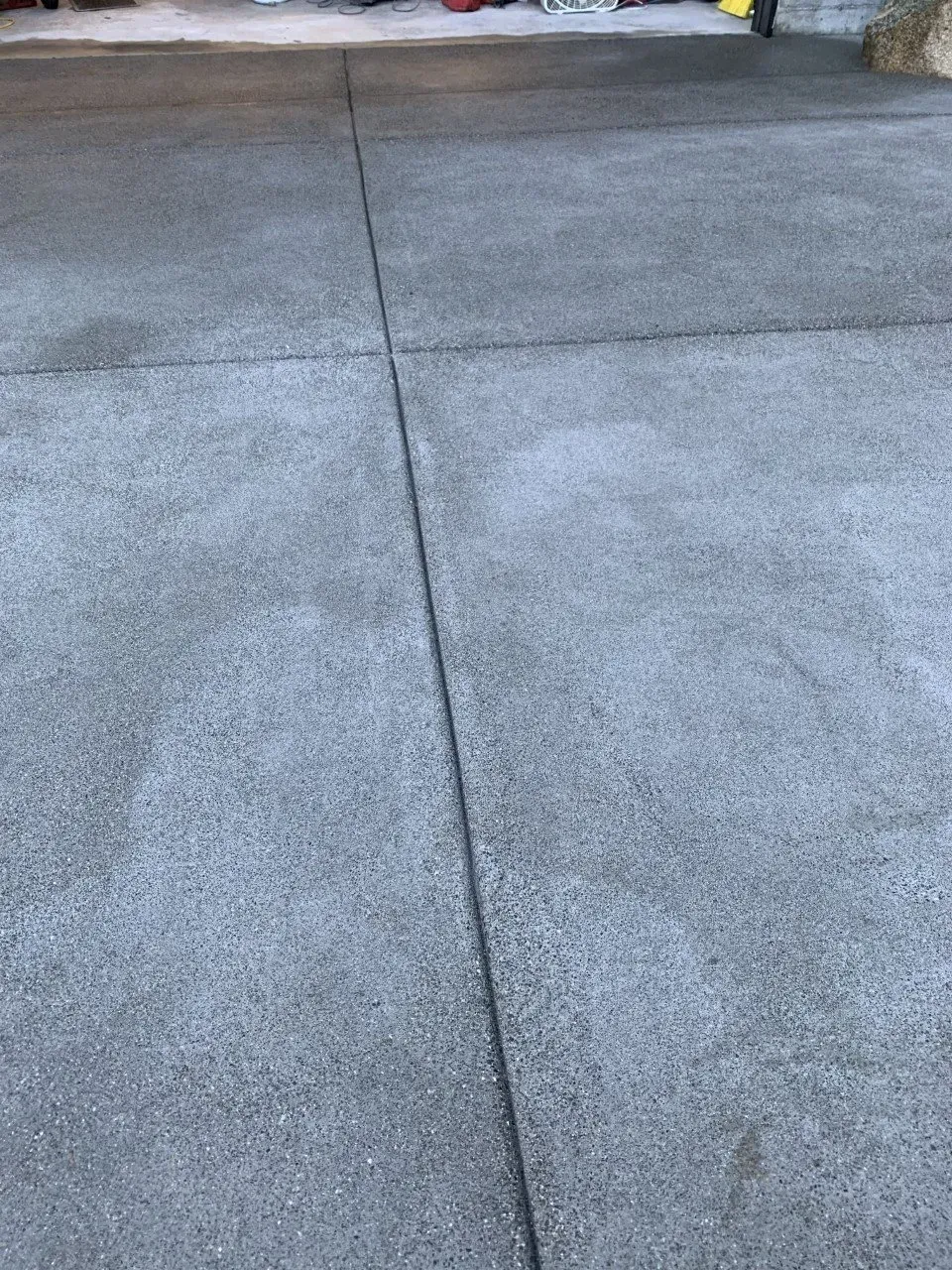 Concrete driveway with a long seam line and slightly wet-looking surface.
