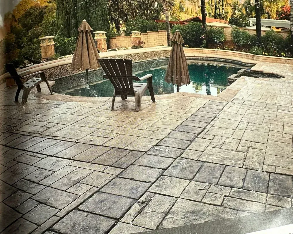 Patio with a small swimming pool, two closed umbrellas, and lounge chairs in a landscaped courtyard